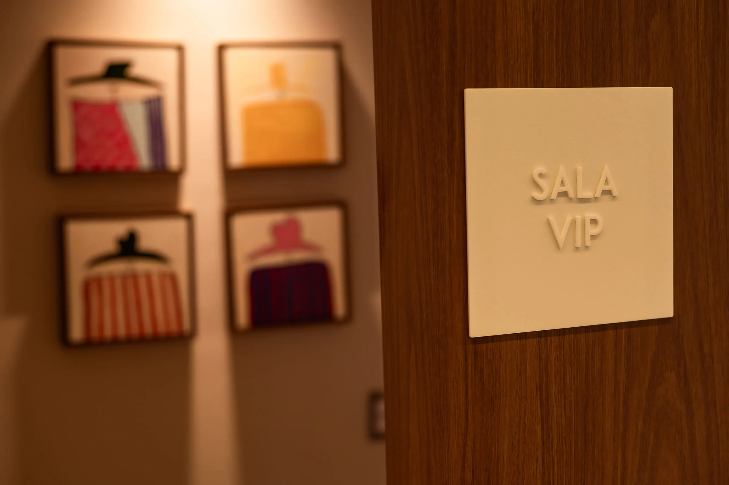 Placa Sala VIP em painel de nogueira ao lado de quatro quadros